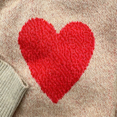 Close-up detail of the pink heart knit design on the sleeve of the heather cream Heart On My Sleeve sweater by Jedd