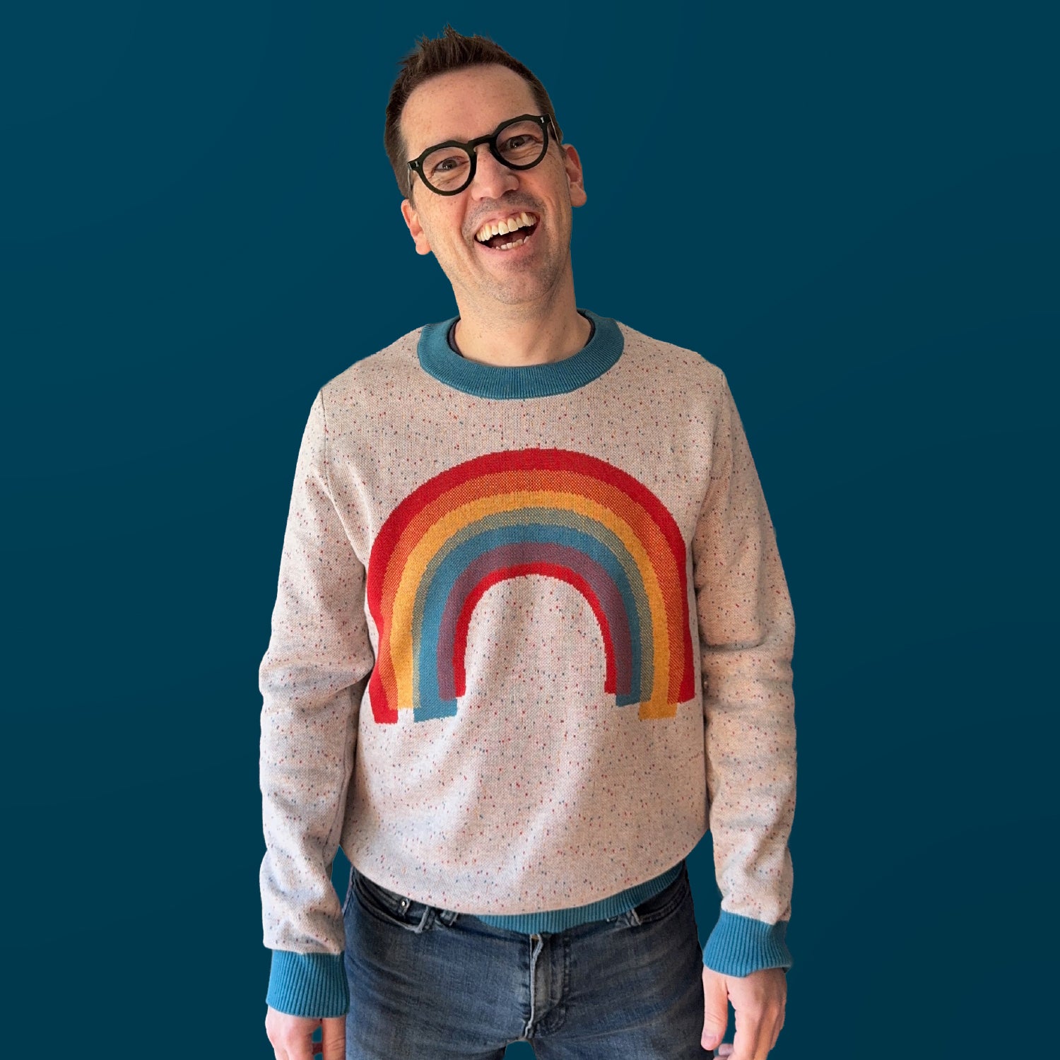 Jedd wearing the Over the Rainbow colorful graphic knit sweater — artist-made designer knitwear full of color