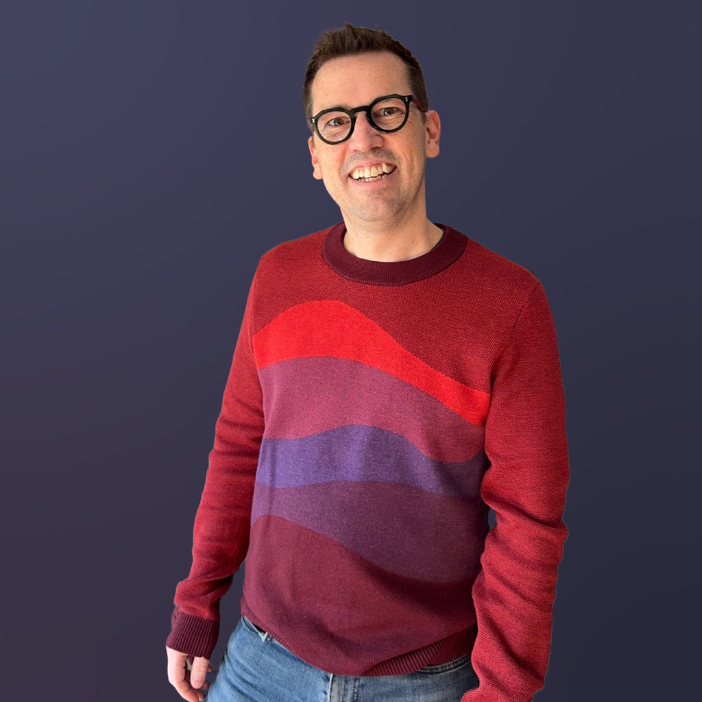 Jedd wearing the Horizons red graphic knit sweater — bold landscape knitwear, artist-designed designer fashion