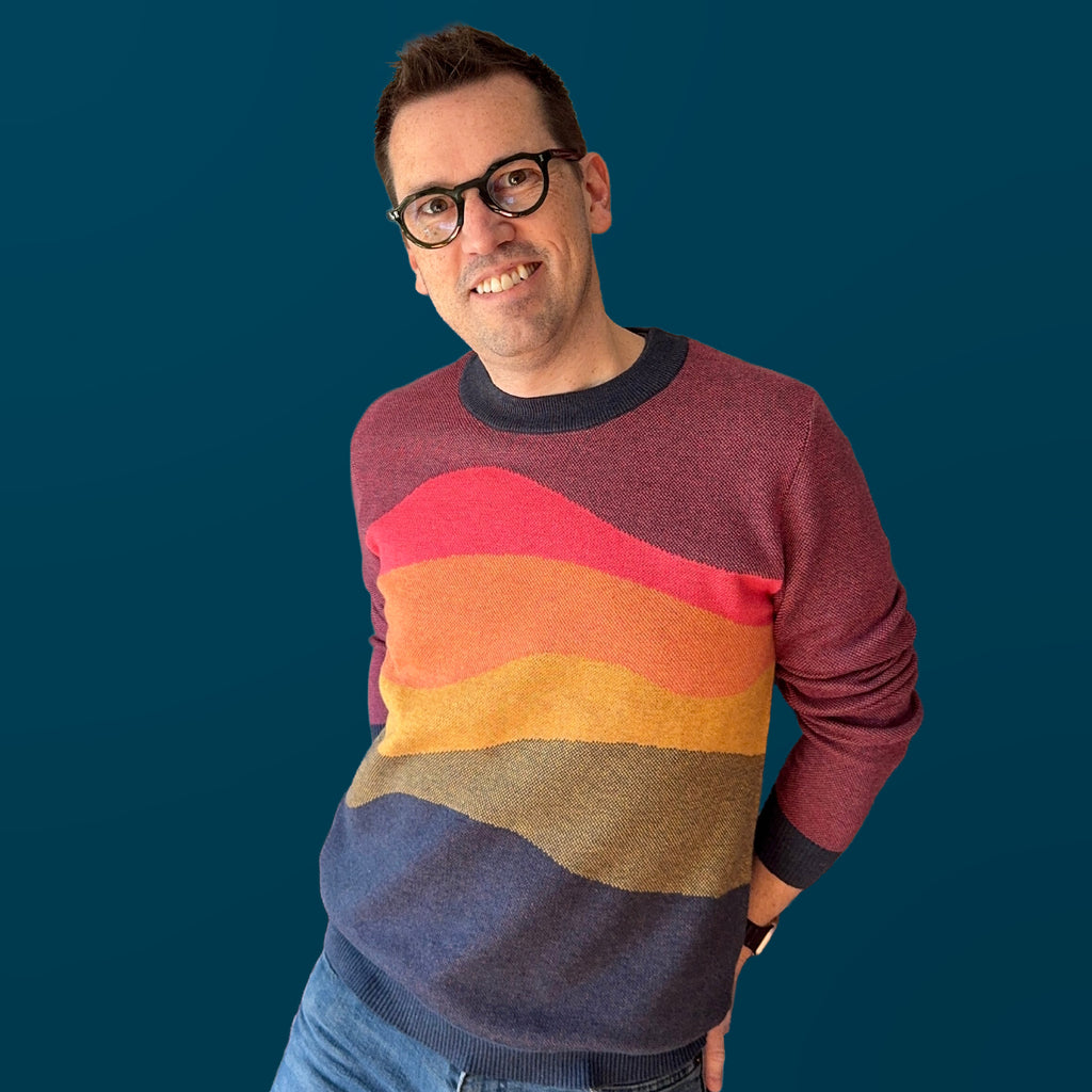 Jedd wearing the Horizons sunset graphic knit sweater — artist-designed layered colorway knitwear