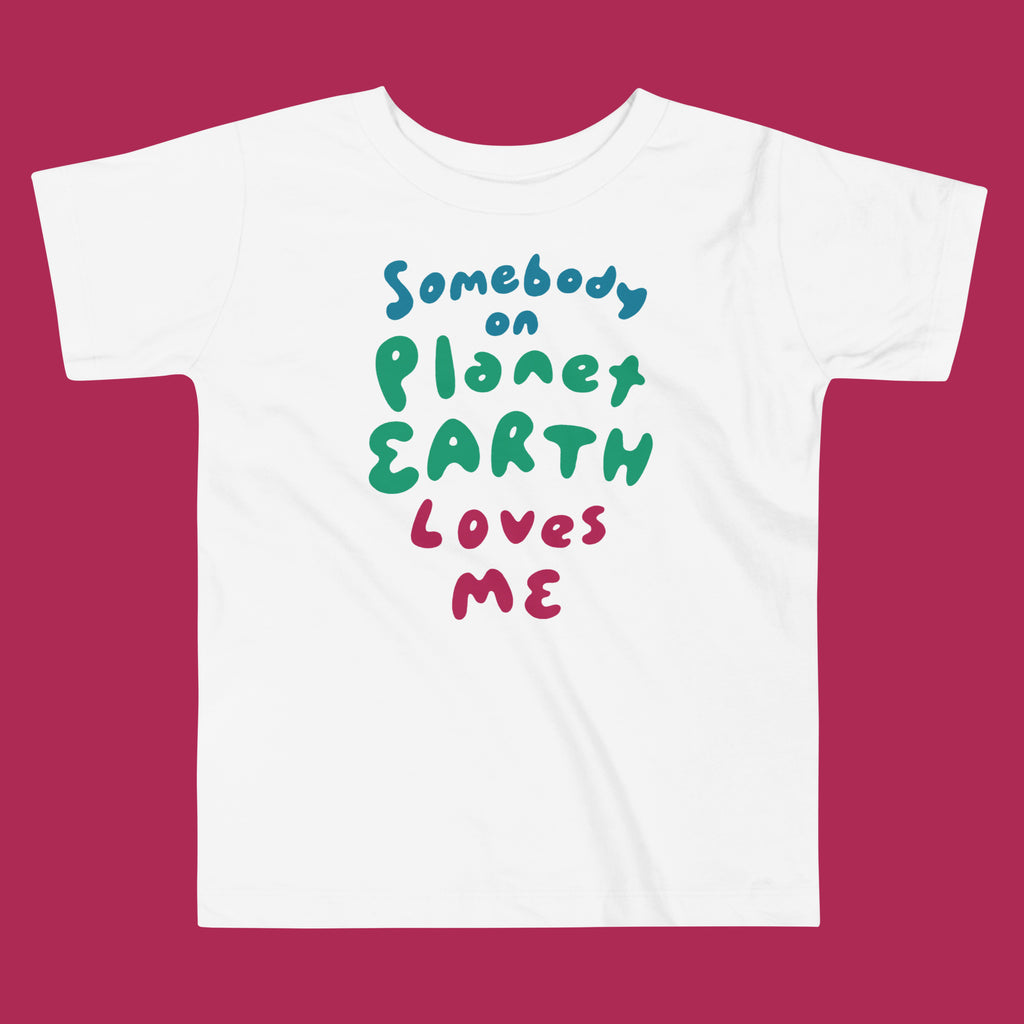 White t-shirt with colorful text 'Somebody on Planet Earth Loves Me' on a magenta background