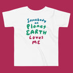 White t-shirt with colorful text 'Somebody on Planet Earth Loves Me' on a magenta background
