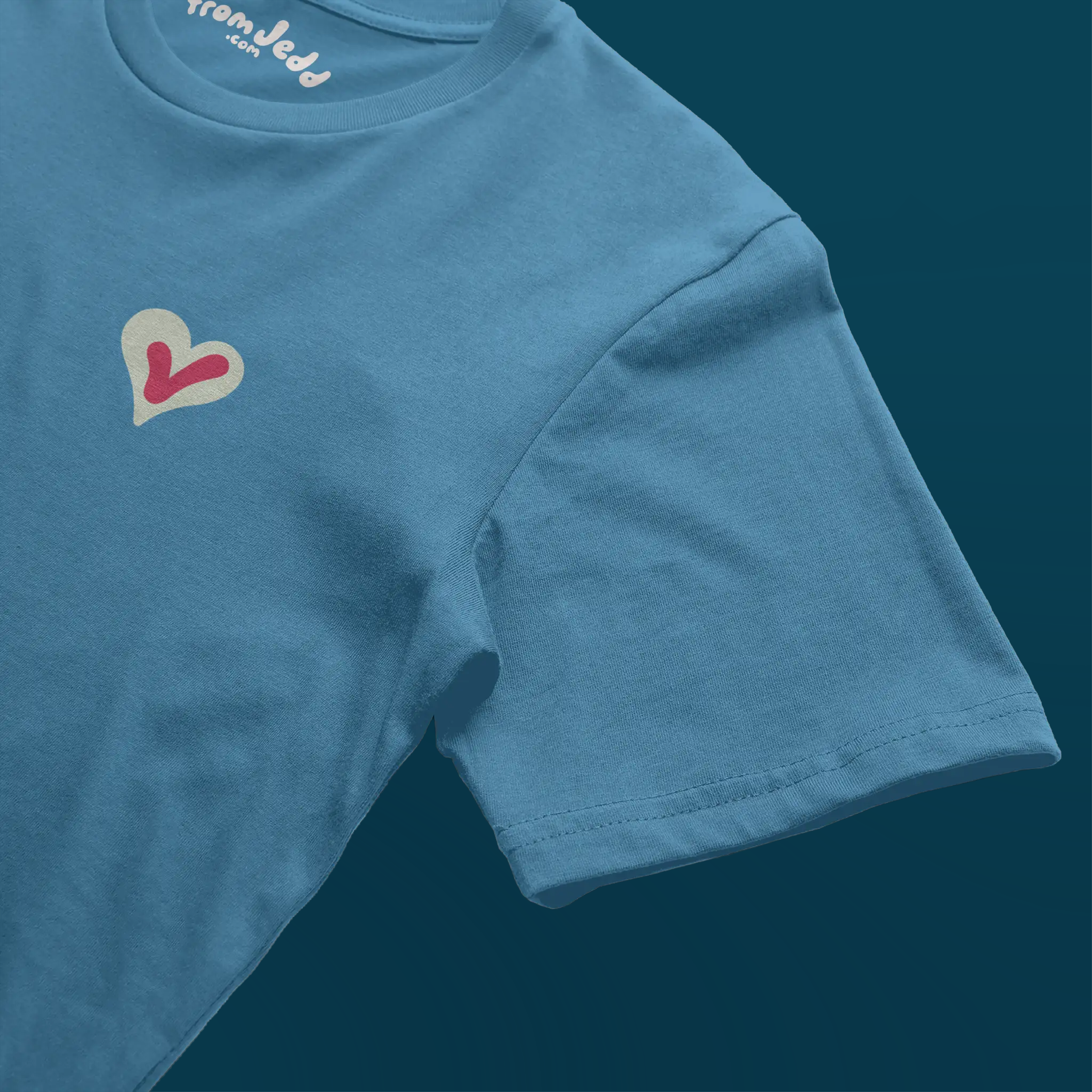Detail of the sleeve on a blue t-shirt with a heart and a voting check mark design and an inside neck logo that says From Jedd