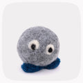 A gray felted ball with eyeballs and blue feet.