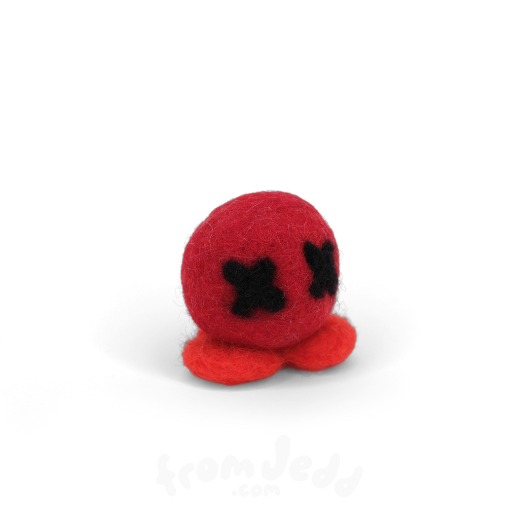 A small red felt octopus toy with black stitched eyes, photographed on a clean white background.