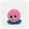 A pink felted ball with eyeballs and blue feet.
