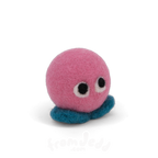 A pink felt creature with two eyes and teal feet.