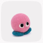 A pink felted ball with eyeballs and blue feet.