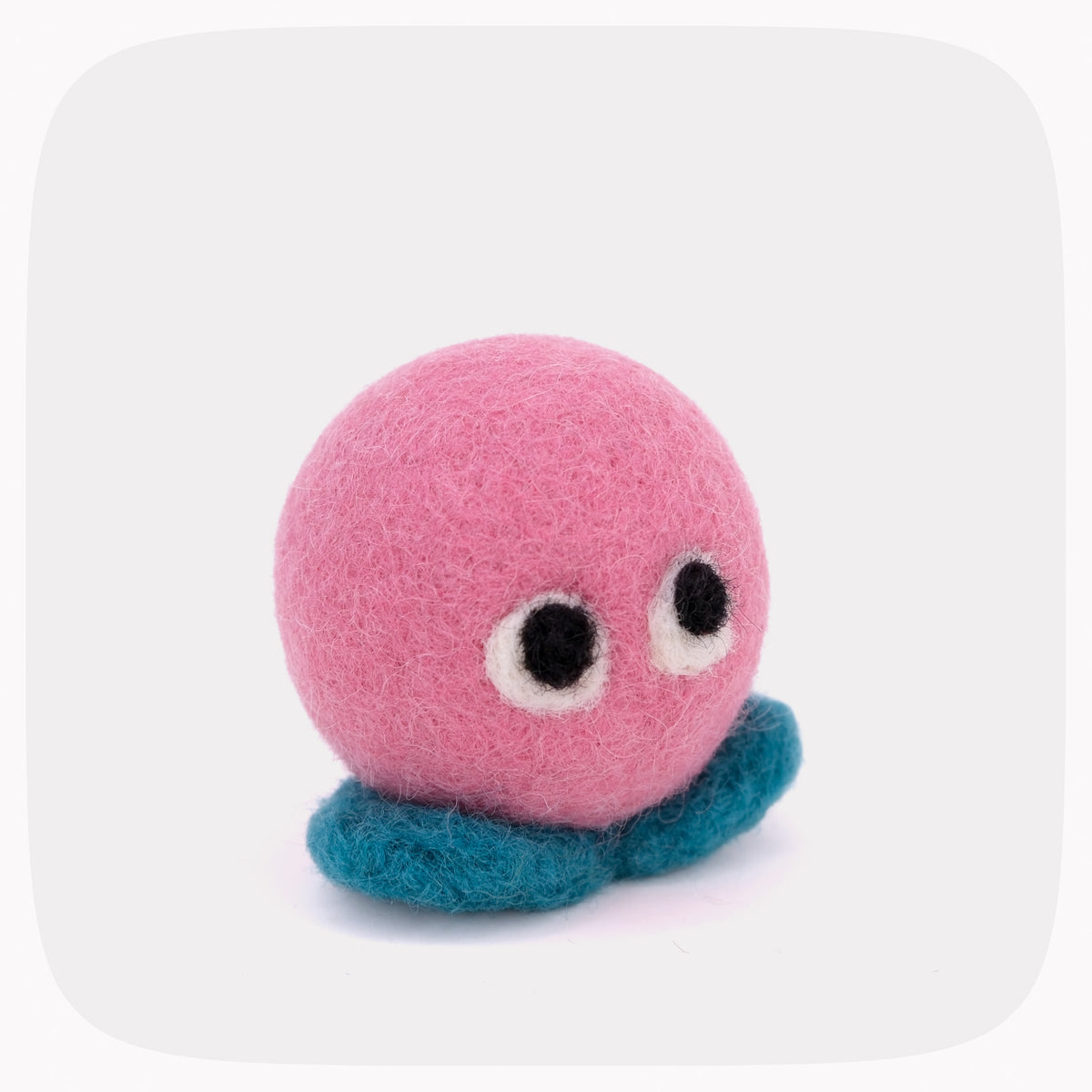 A pink felted ball with eyeballs and blue feet.