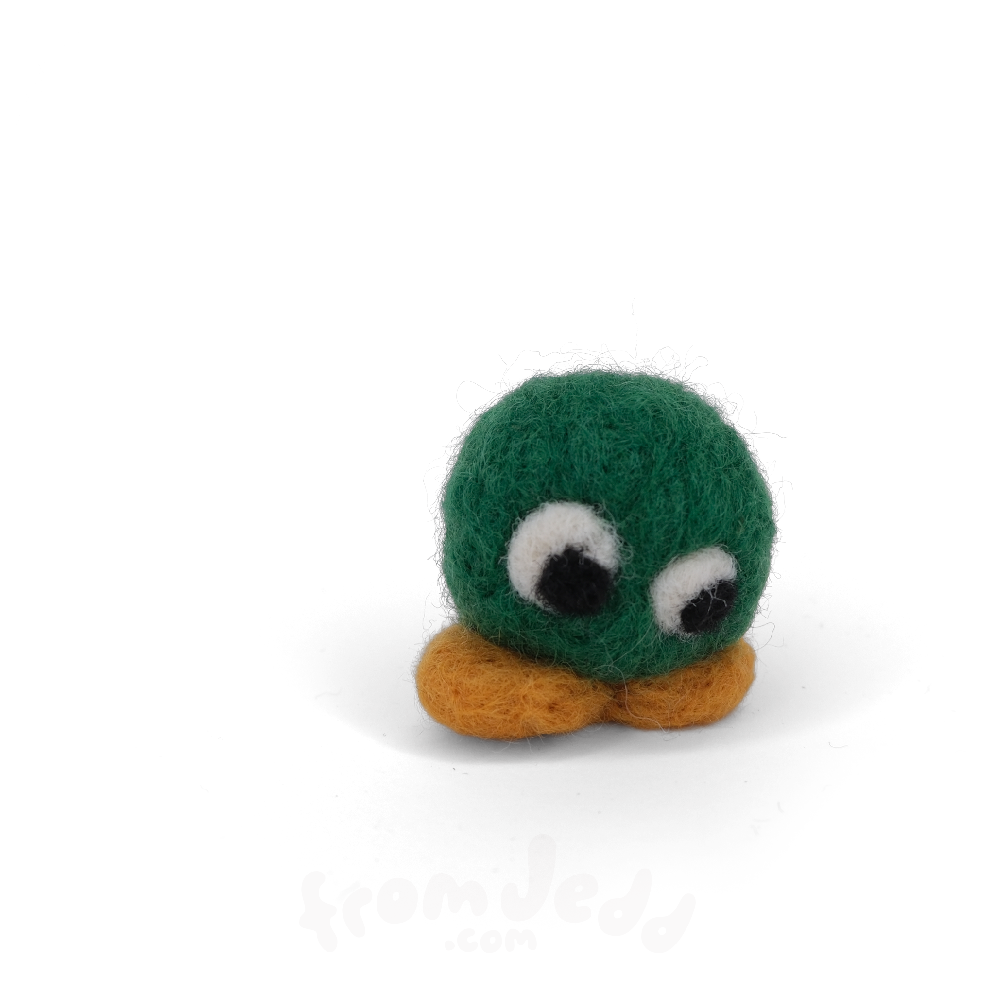 A small felted wool character toy with a round green head, large white eyes with black pupils, and a rounded orange base, photographed on a clean white background.