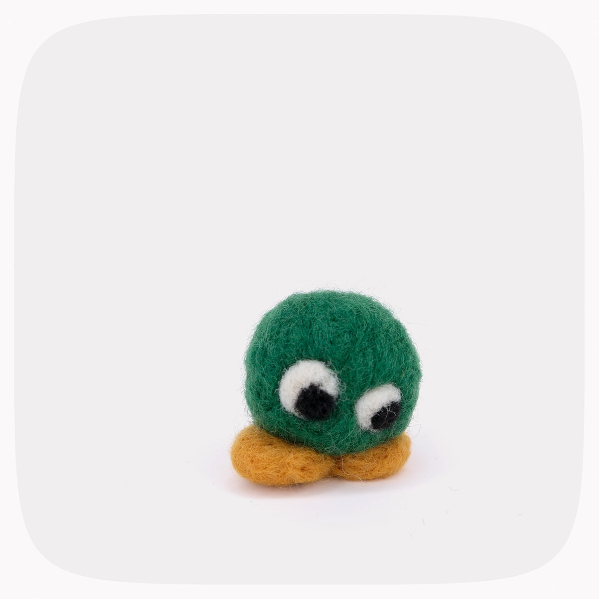 A green felted circle with eyes looking down and yellow feet.