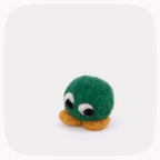 A green felted circle with eyes looking down and yellow feet.
