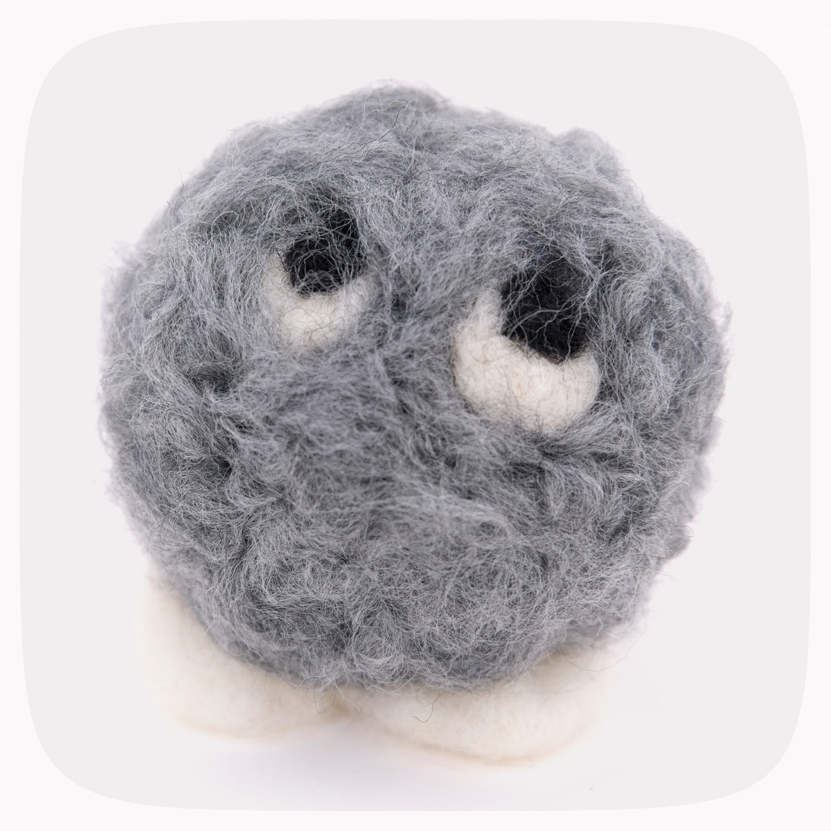 A gray fuzzy felted ball with eyeballs looking up and white feet.