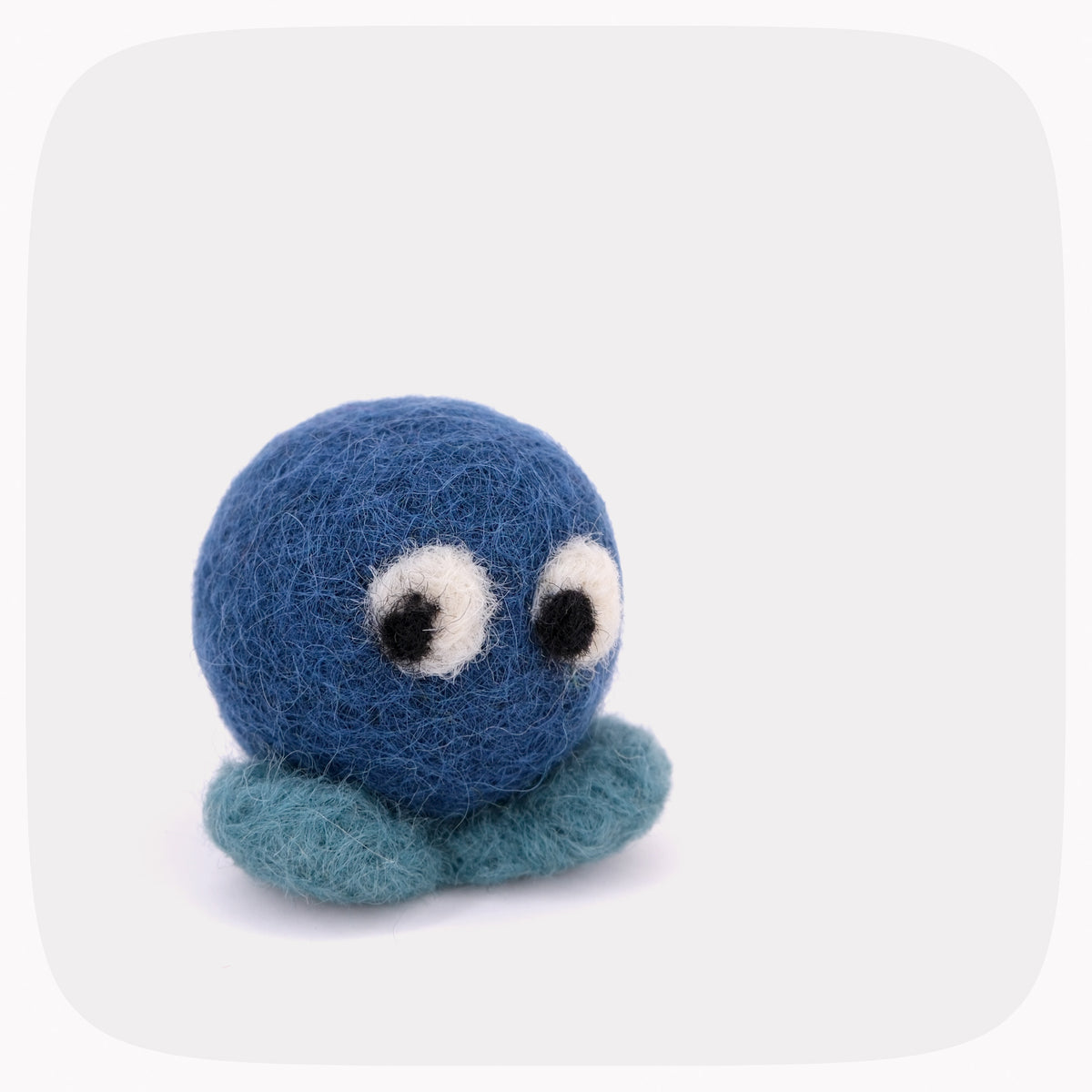 A blue felted ball with eyes looking down with lighter blue feet.
